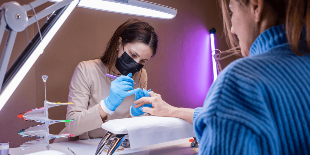 Nail technician applying gel polish to a client's nails in a salon.
