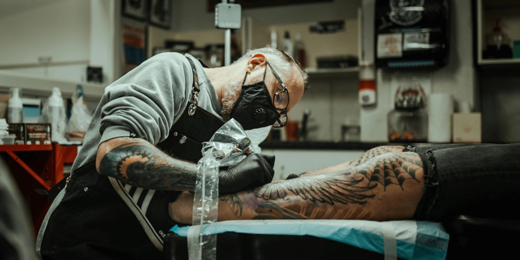 Tattoo artist carefully applying a tattoo design in a clean studio environment.